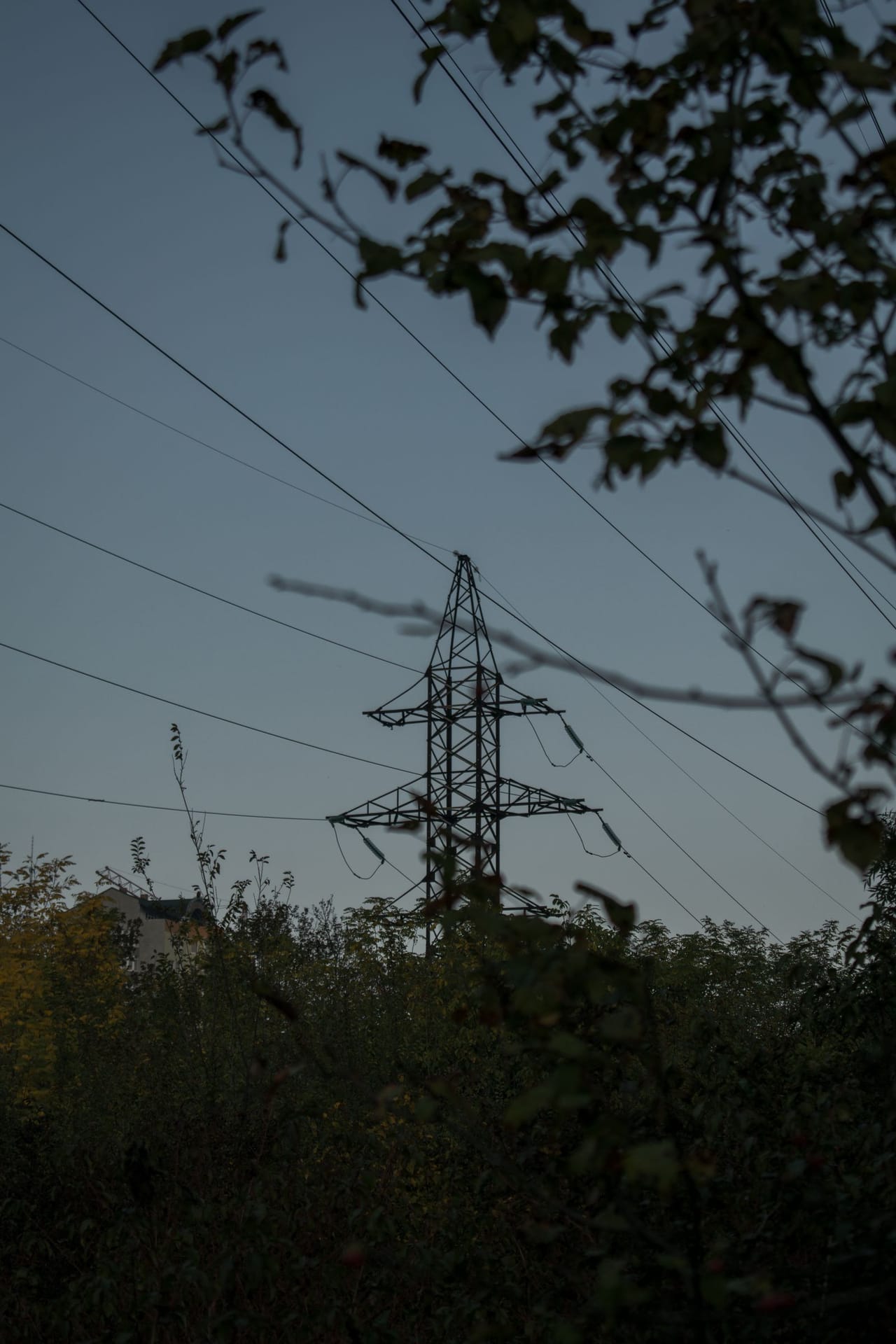 High-voltage transmission tower and powerline corridor silhouetted at dusk